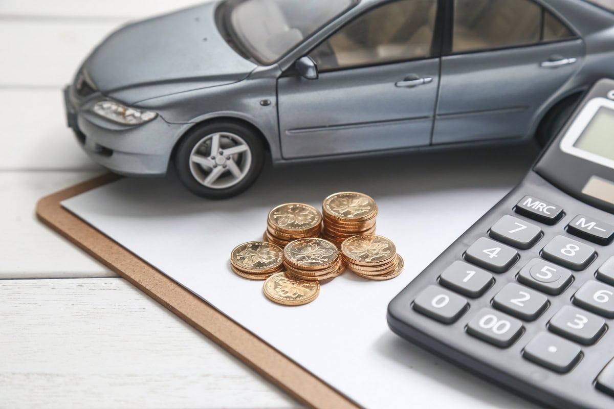 A car title loan concept with a model car, coins, and a calculator on a table